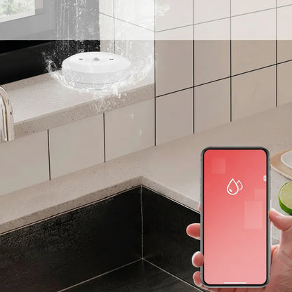 Smart home water damage sensor alerting on a smartphone app with water splashing on a kitchen counter.