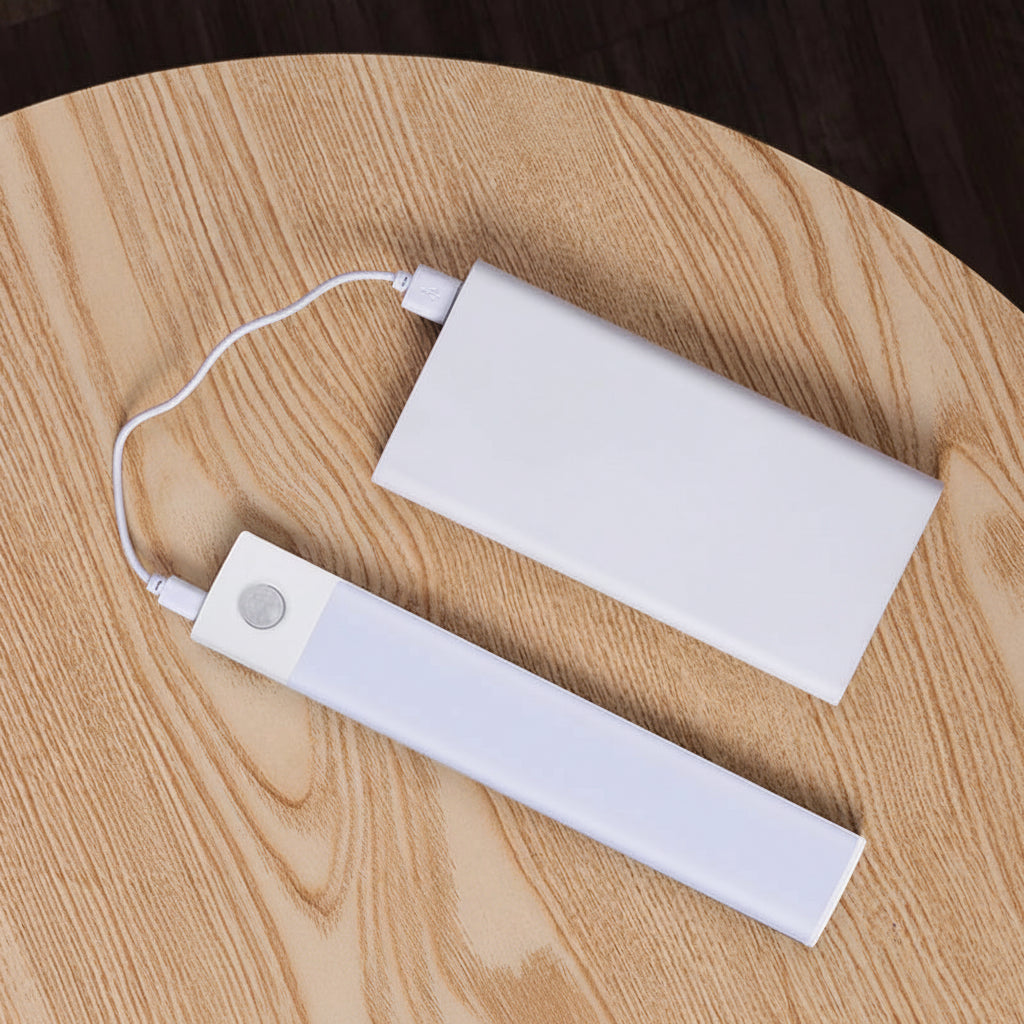 White power bank with micro USB interface on a wooden surface, showing charging status indicators.